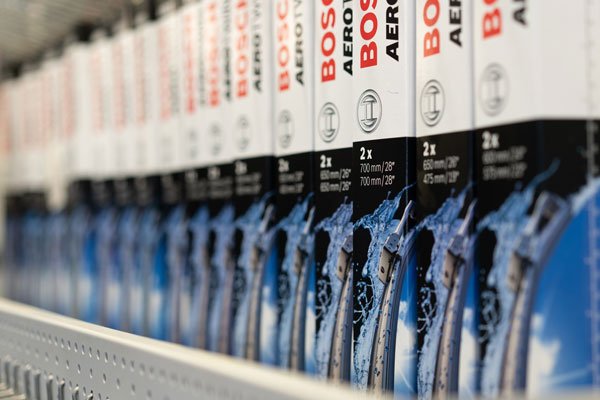 Verschiedene Scheibenwischer der Firma Bosch stehen in einem Regal.